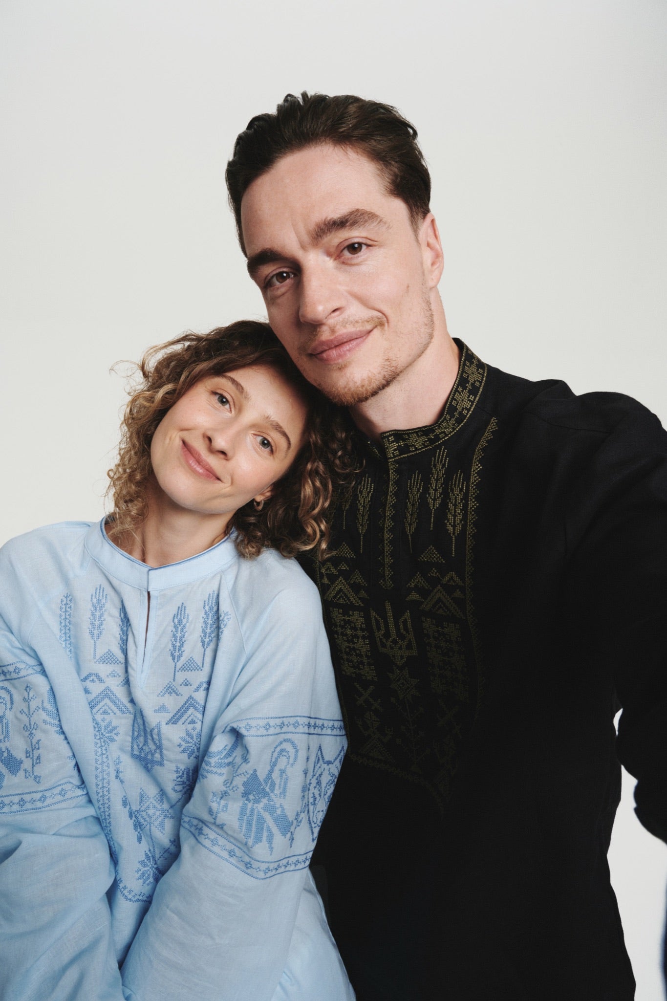 Couple in Saint Javelin vyshyvankas: light-blue women's shirt with blue embroidery, black men's shirt with olive embroidery