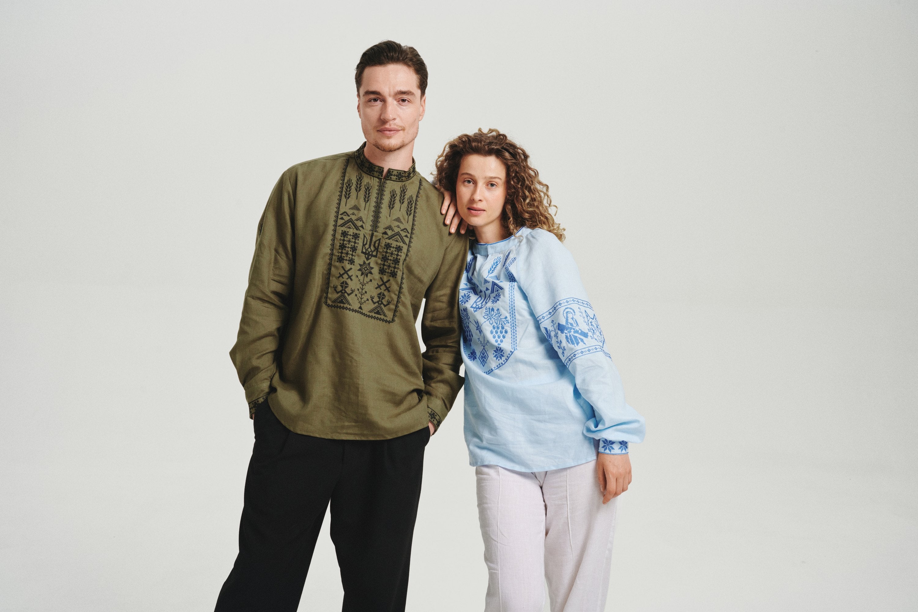 Couple wearing Saint Javelin vyshyvankas: olive men's shirt with black embroidery and the first women's vyshyvanka in light blue