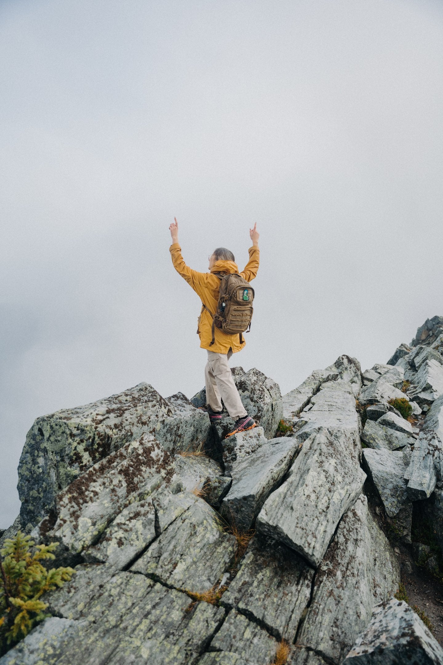 Hiker with a Saint Javelin backpack raising their arms on a summit ridge in the Carpathian Mountains, Ukraine